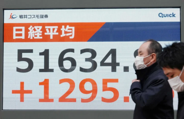 يمر المشاة أمام لوحة إلكترونية تعرض أرقام مؤشر «نيكي» في بورصة طوكيو (أ.ف.ب)